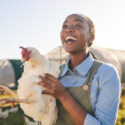 A woman holding a chicken that she's checking in on